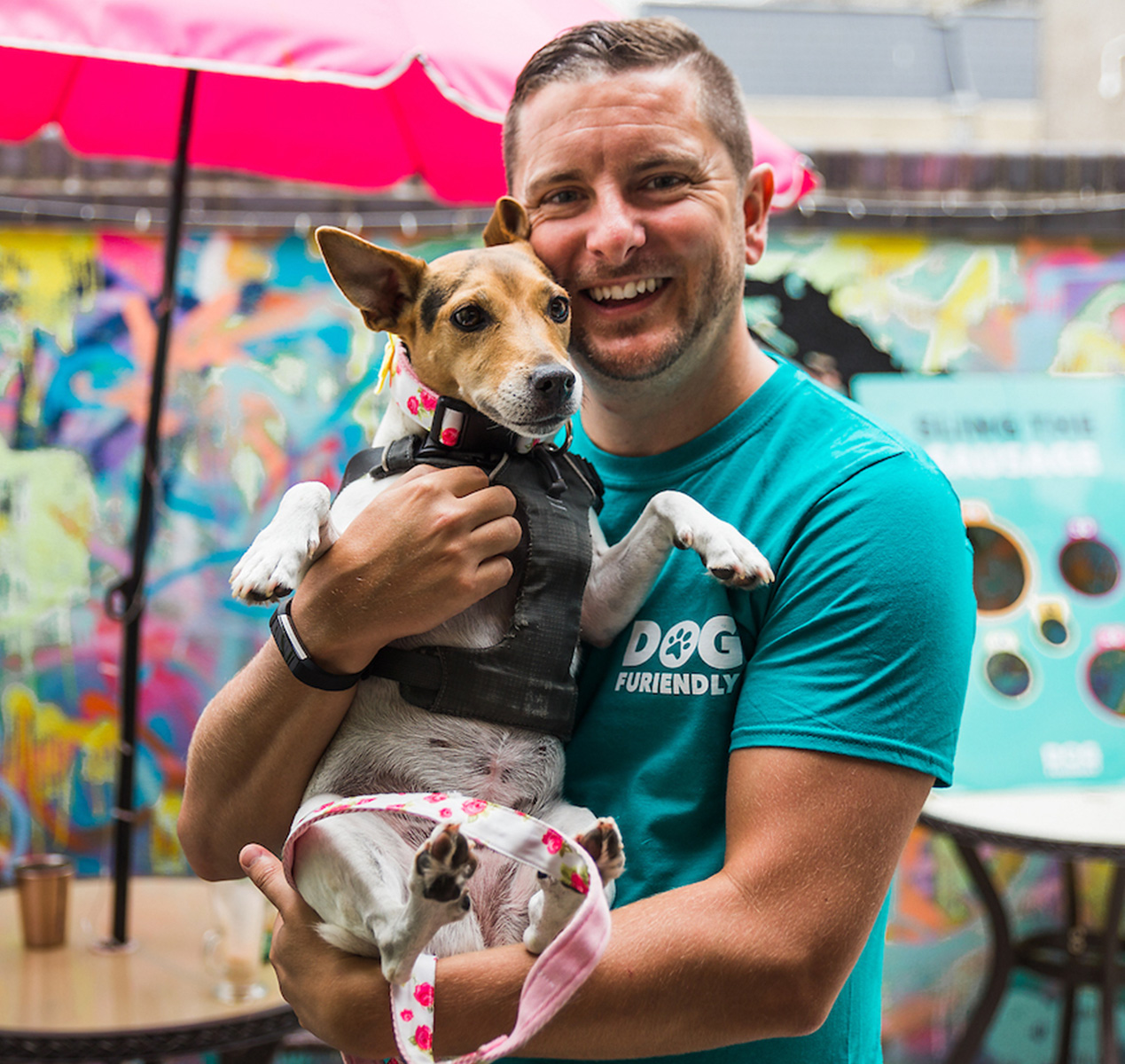 A man smiling, holding a dog in his arms.