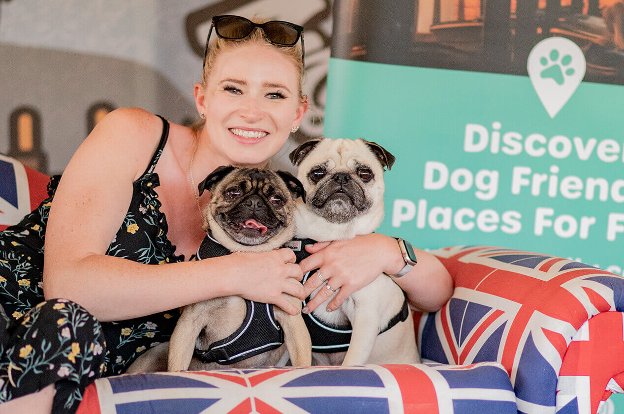 A woman sat down hugging her two pugs at Dogstival festival.