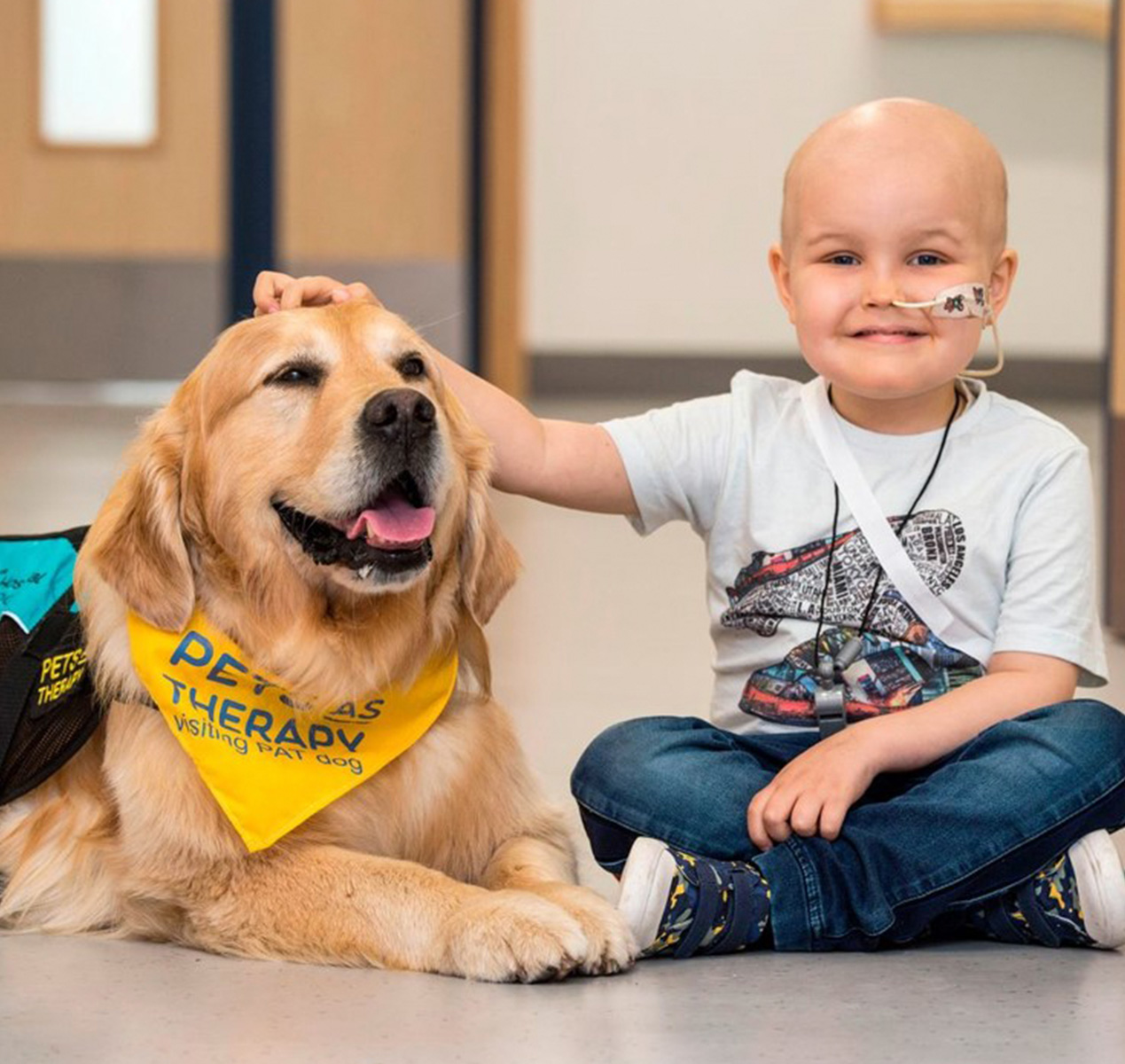 A therapy dog led down next to a small child.